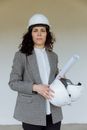 Female architect in safety gear holding blueprints, showcasing professionalism.